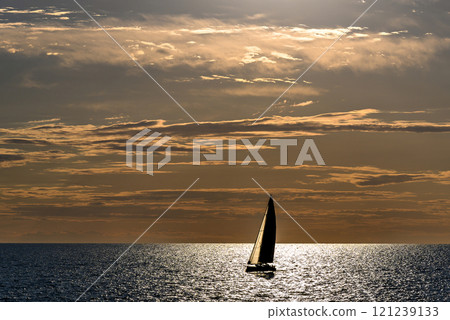 View of a sailing boat at sunset passing in front of the Artruxt Lighthouse, Cuidadela, Menorca, Balearic Islands, Spain View of a sailing boat at sunset passing in front of the Artruxt Lighthouse, Cuidadela, Menorca, Balearic Islands, Spain 121239133