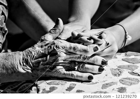 Affection and tenderness of a granddaughter towards her grandmother. Signs of aging in the hands. Black and white effect Affection and tenderness of a granddaughter towards her grandmother. Signs of aging in the hands. Black and white effect 121239270