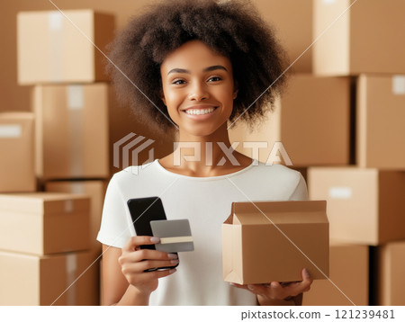 Smiling young woman holding a smartphone, credit card, and package 121239481