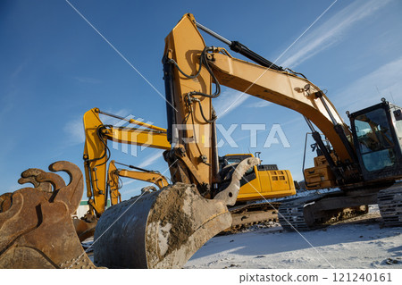 Multiple excavators operating on a construction site in winter conditions. Multiple excavators operating on a construction site in winter conditions. 121240161