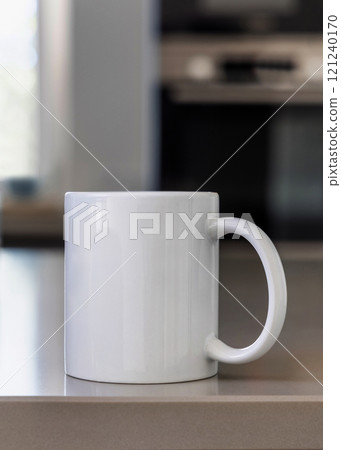Closeup of white blank coffee mug on grey kitchen table over blured kitchen interior, mockup Closeup of white blank coffee mug on grey kitchen table over blured kitchen interior, mockup 121240170