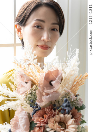 Middle-aged woman holding a bouquet indoors 121241811