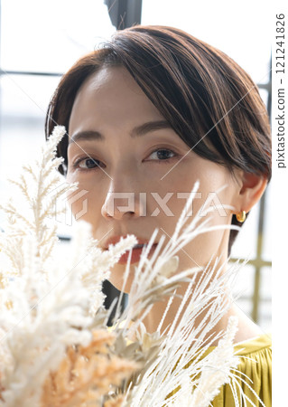 Middle-aged woman holding a bouquet indoors Middle-aged woman holding a bouquet indoors 121241826