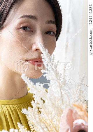 Middle-aged woman holding a bouquet indoors Middle-aged woman holding a bouquet indoors 121241828