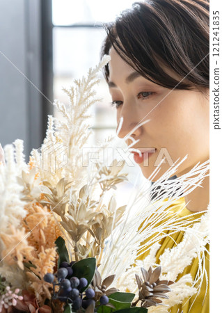 Middle-aged woman holding a bouquet indoors 121241835
