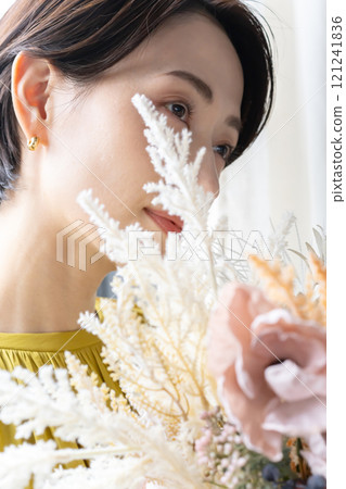 Middle-aged woman holding a bouquet indoors 121241836