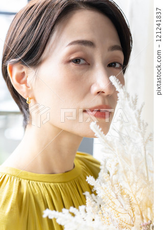 Middle-aged woman holding a bouquet indoors 121241837
