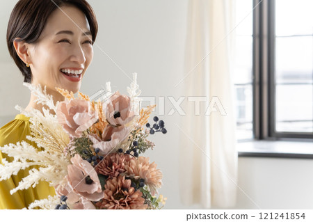 Middle-aged woman holding a bouquet indoors Middle-aged woman holding a bouquet indoors 121241854