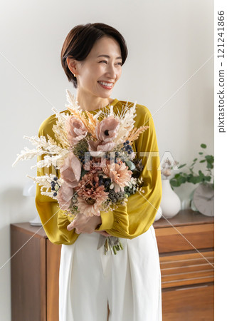 Middle-aged woman holding a bouquet indoors Middle-aged woman holding a bouquet indoors 121241866