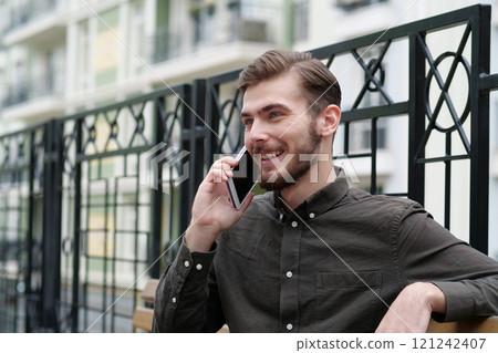 Young handsome businessman sits on bench and speaks on smartphone 121242407