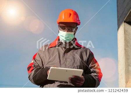 African american builder in medical mask makes notes in tablet PC 121242439