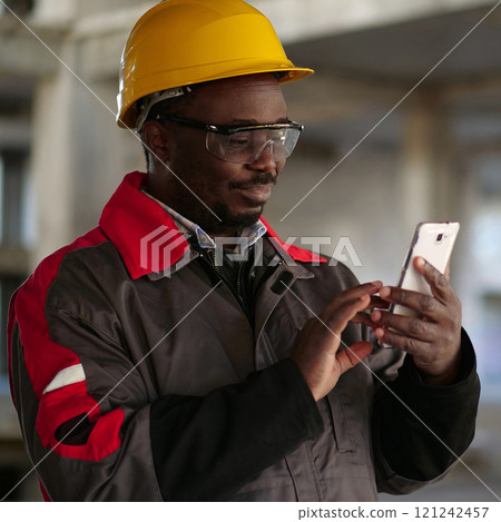 African american workman with smartphone at construction site 121242457