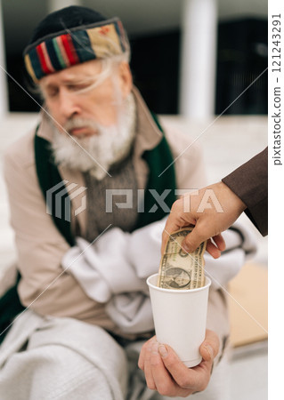 Close-up vertical cropped shot of unrecognizable kind man giving paper money to senior homeless beggar male sitting on urban street, symbolizing hope and generosity in face of poverty and unemployment Close-up vertical cropped shot of unrecognizable kind man giving paper money to senior homeless beggar male sitting on urban street, symbolizing hope and generosity in face of poverty and unemployment 121243291