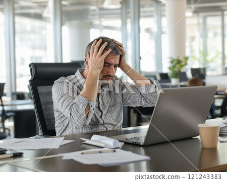 A Stressed Businessman Confronting Numerous Work Challenges in a Modern Office Environment 121243383