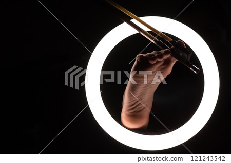 female legs with a violin bow in close-up in a round lamp. the concept of playing the violin .foot fetishism 121243542