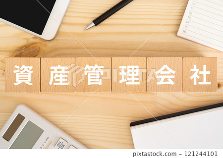 Blocks with asset management company logo, smartphone, calculator 121244101