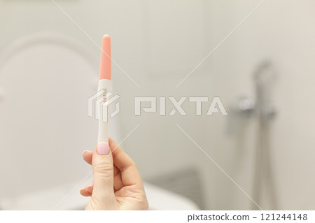Holding positive pregnancy test in rest room Holding positive pregnancy test in rest room 121244148