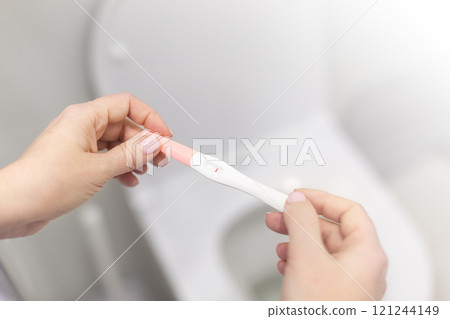 Holding positive pregnancy test in rest room Holding positive pregnancy test in rest room 121244149