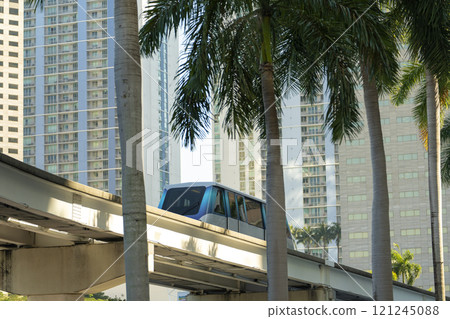 Public transportation in downtown Miami in Florida USA. Metrorail city train car on high railroad over street traffic between skyscraper buildings in modern American megapolis 121245088