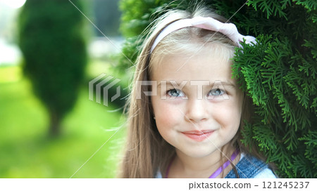 Portrait of pretty little child girl standing outdoors in summer park smiling happily. 121245237