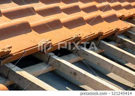 Overlapping rows of yellow ceramic roofing tiles mounted on wood Overlapping rows of yellow ceramic roofing tiles mounted on wood 121245414