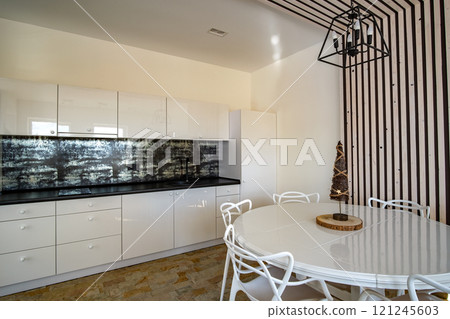 Interior of modern spacious kitchen with white walls, decorative wooden elements, contemporary furniture and big soft couch. Interior of modern spacious kitchen with white walls, decorative wooden elements, contemporary furniture and big soft couch. 121245603