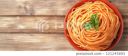 A bowl of spaghetti topped with a fresh basil leaf, rustic wooden background 121245893