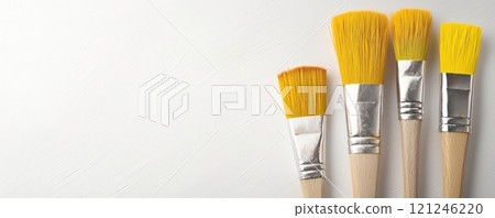 A close-up of paintbrushes with yellow bristles against a white background, 121246220