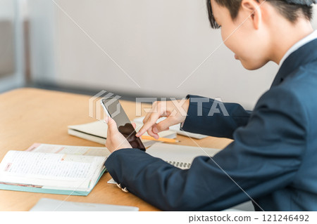 一名女國中生坐在課桌前操作智慧型手機的後方視野(智慧型手機依賴、智慧型手機成癮、智慧型手機脖子) 一名女國中生坐在課桌前操作智慧型手機的後方視野(智慧型手機依賴、智慧型手機成癮、智慧型手機脖子) 121246492