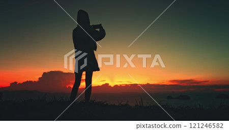 Girl silhouette walking sunset sky ocean nature beauty. Female make photo on her phone standing over sea, enjoy bright colorful sky. Outdoor lifestyle travel, summer holiday vacation, 121246582