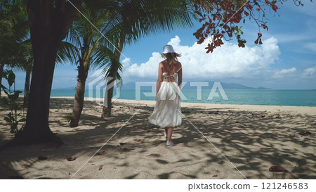 Woman joyfully strolls on a white beach in thailand, heading towards the turquoise sea, embracing her summer vacation Woman joyfully strolls on a white beach in thailand, heading towards the turquoise sea, embracing her summer vacation 121246583