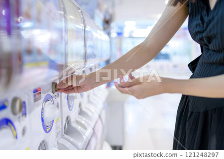 Young woman spinning a capsule toy, Gacha 121248297