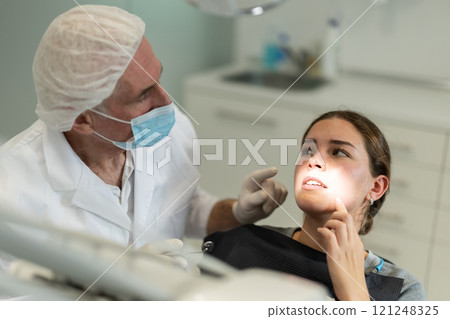 Elderly male dentist examining female patient Elderly male dentist examining female patient 121248325