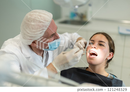 Elderly male dentist examining female patient Elderly male dentist examining female patient 121248329