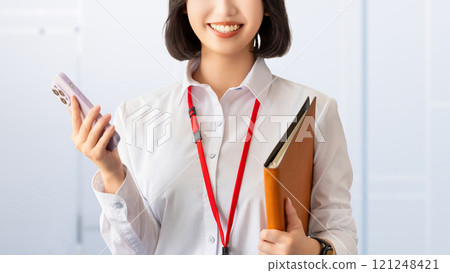 Smiling young woman/businesswoman holding a smartphone 121248421