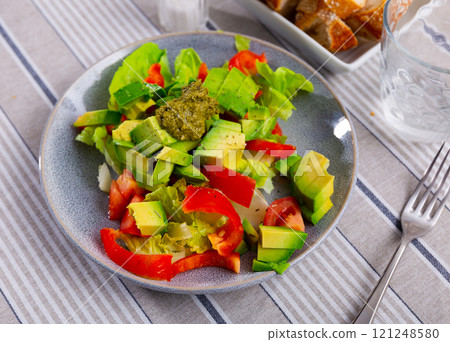 Plate contains portion of salad from fresh vegetables and pesto sauce. Plate contains portion of salad from fresh vegetables and pesto sauce. 121248580
