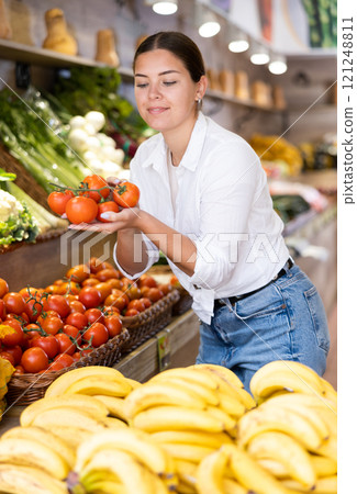 Portrait of positive satisfied girl buying tomatoes in grocery shop 121248811