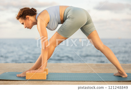 Yoga practice on embankment, female athlete fulfil carry out Parshvottanasana 121248849