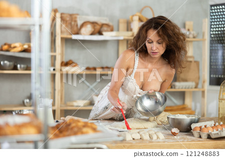 Adult woman in dress greasing dough Adult woman in dress greasing dough 121248883