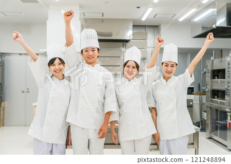 Chefs and cooks in chef coats standing in the kitchen (fist pump) 121248894