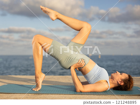 Yoga practice on embankment, female athlete fulfil carry out chatush padasana 121248895