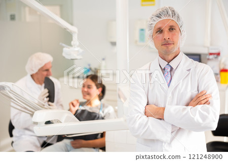 Man doctor dentist is standing in dental office, clinic 121248900