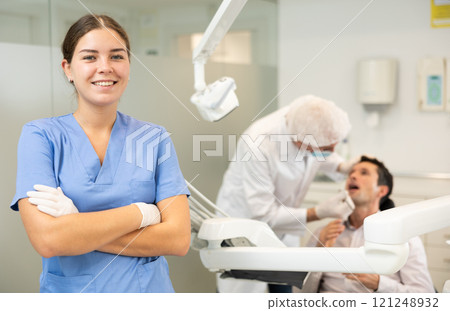 Young woman nurse in blue suit is standing in dental office, clinic Young woman nurse in blue suit is standing in dental office, clinic 121248932