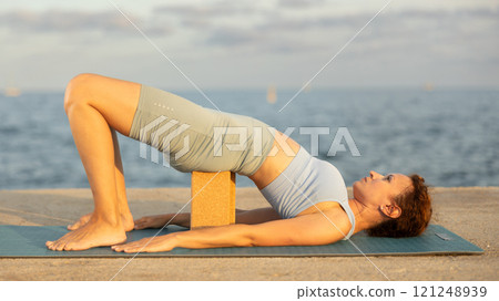 Yoga practice on embankment, female athlete fulfil carry out chatush padasana Yoga practice on embankment, female athlete fulfil carry out chatush padasana 121248939