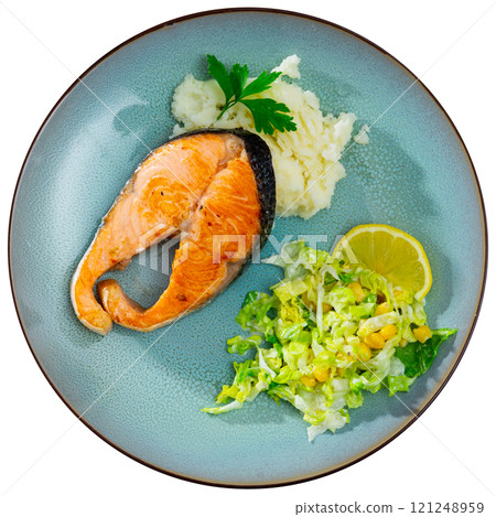 There is large piece of fried salmon on plate, garnished with mashed potatoes, vegetable salad There is large piece of fried salmon on plate, garnished with mashed potatoes, vegetable salad 121248959