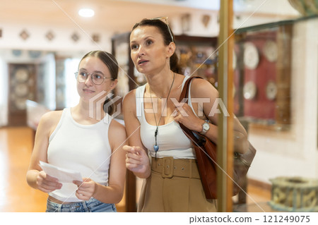 Woman and teenage girl looking at exhibition of tableware 121249075