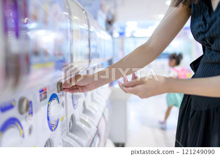 一位年輕女子正在旋轉扭蛋玩具 Gacha，這是成年人沉迷的愛好 121249090