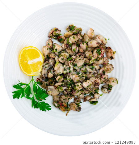 There are pieces of grilled squid on plate. Seafood is complemented with lemon and parsley 121249093