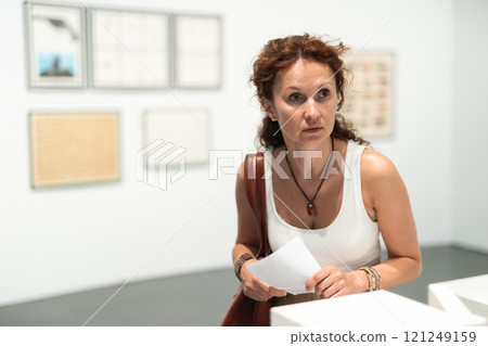 Woman observing photographs on display in photo gallery 121249159