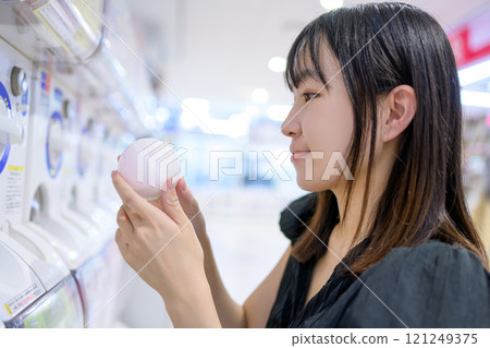 年輕女子旋轉膠囊玩具扭蛋 年輕女子旋轉膠囊玩具扭蛋 121249375